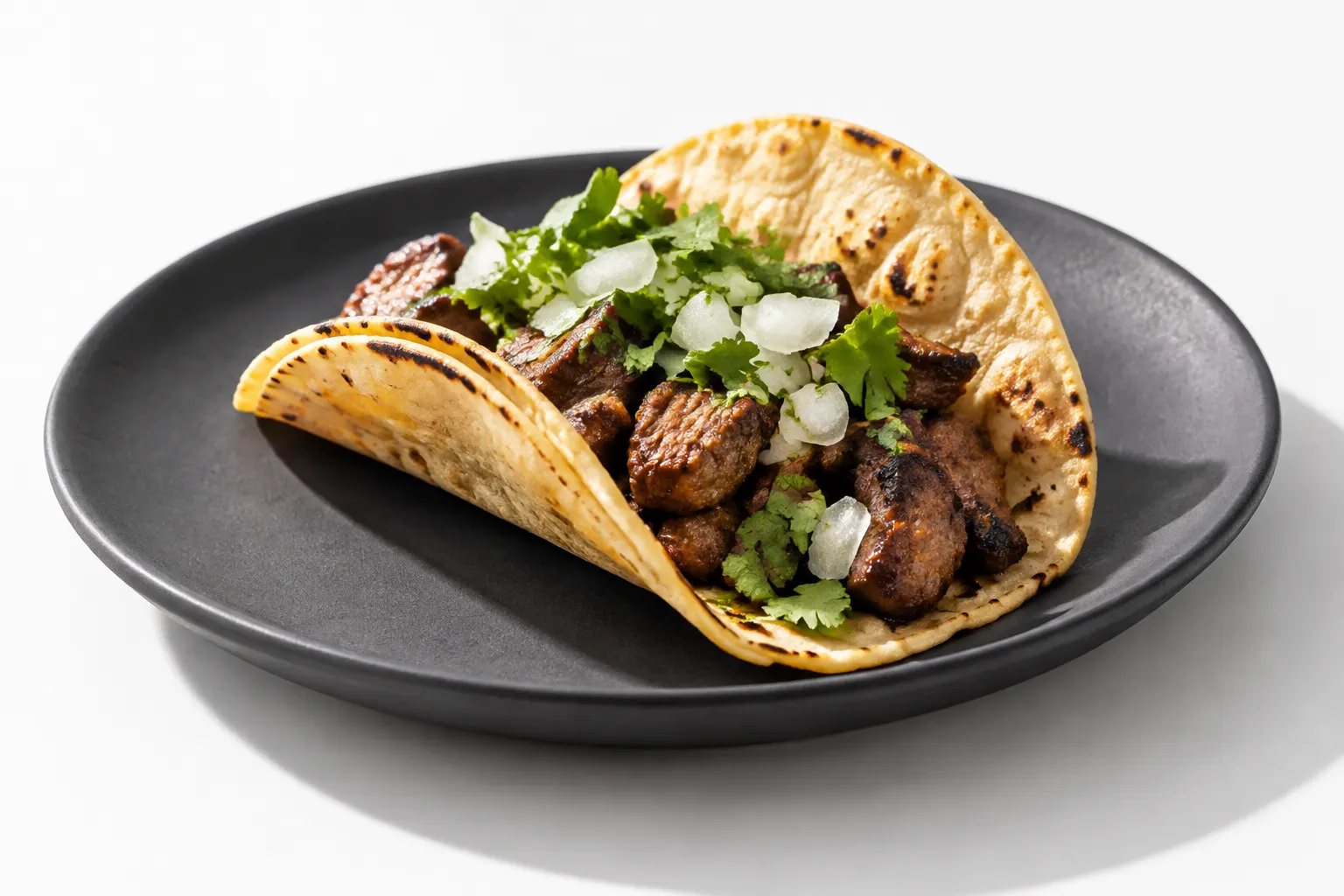 A detailed close-up of a taco on a charcoal plate against a white table.