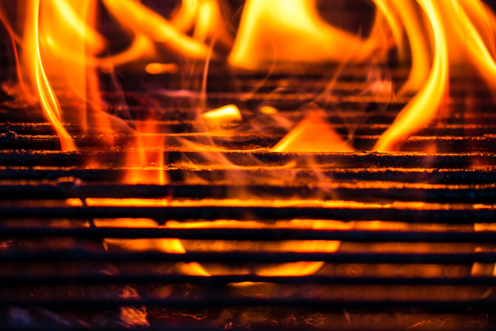 Llamas de carbón encendiéndose bajo la parrilla