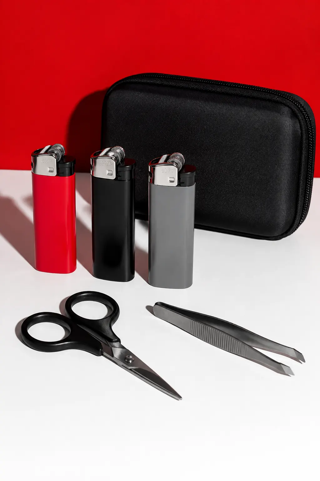 Encendedores lisos y pequeños accesorios ordenados sobre una superficie blanca con fondo rojo.