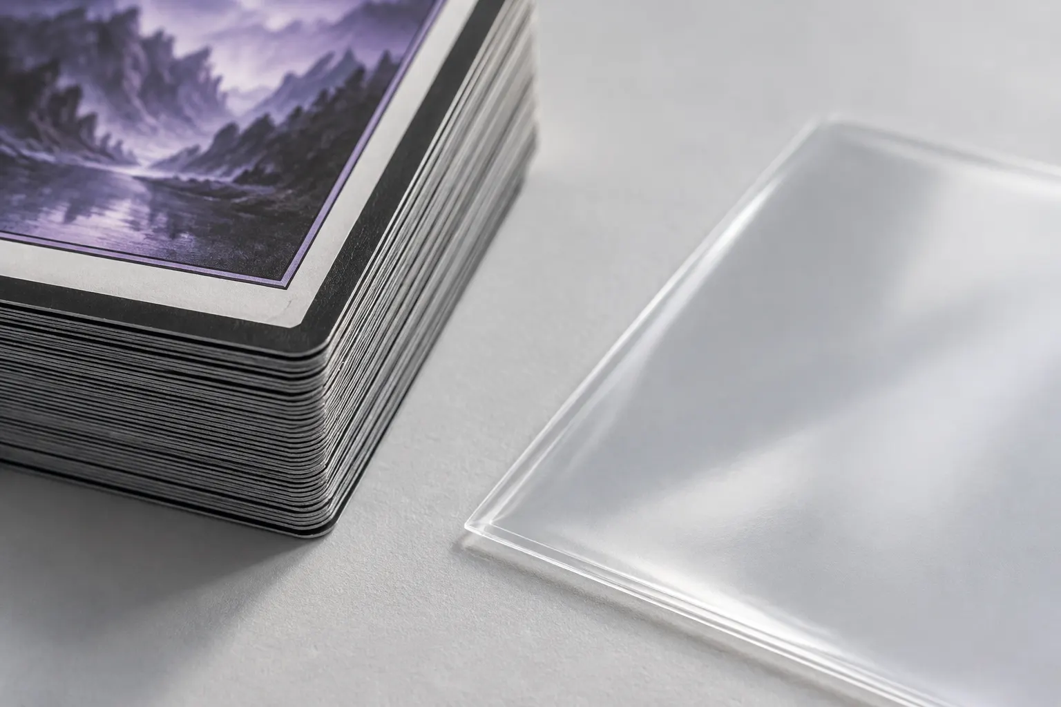 Close view of trading card edges and a clear protective sleeve on a pale surface.
