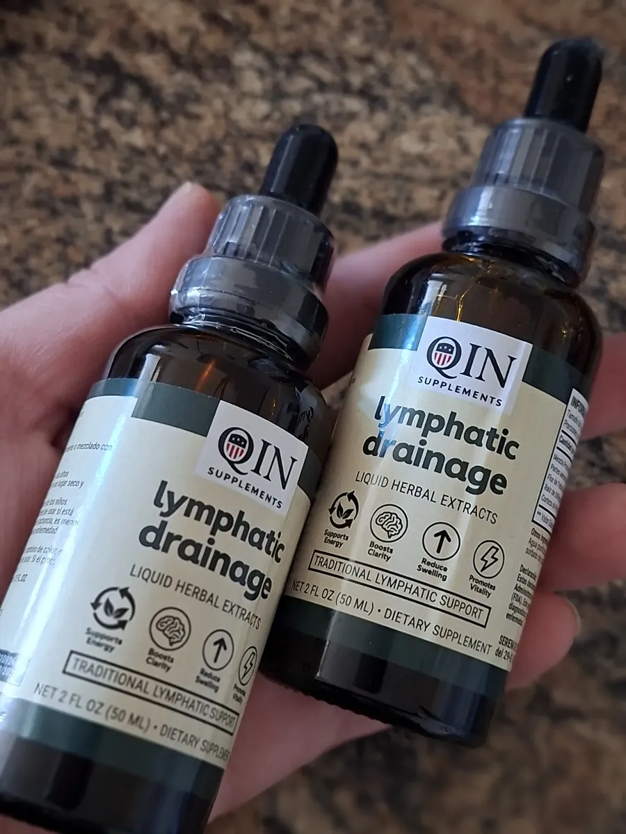 Dos frascos de QIN Lymphatic Drainage sostenidos en la mano