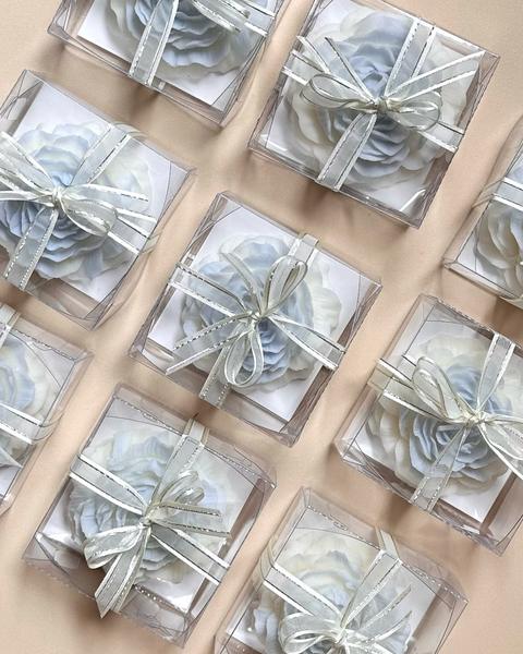 Velas en forma de flor en cajas de acetato con moño