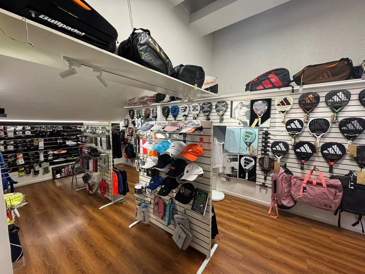 Interior de la tienda Padel Shop Chile en Los Cobres de Vitacura, con muro de palas de pádel y raquetas de tenis