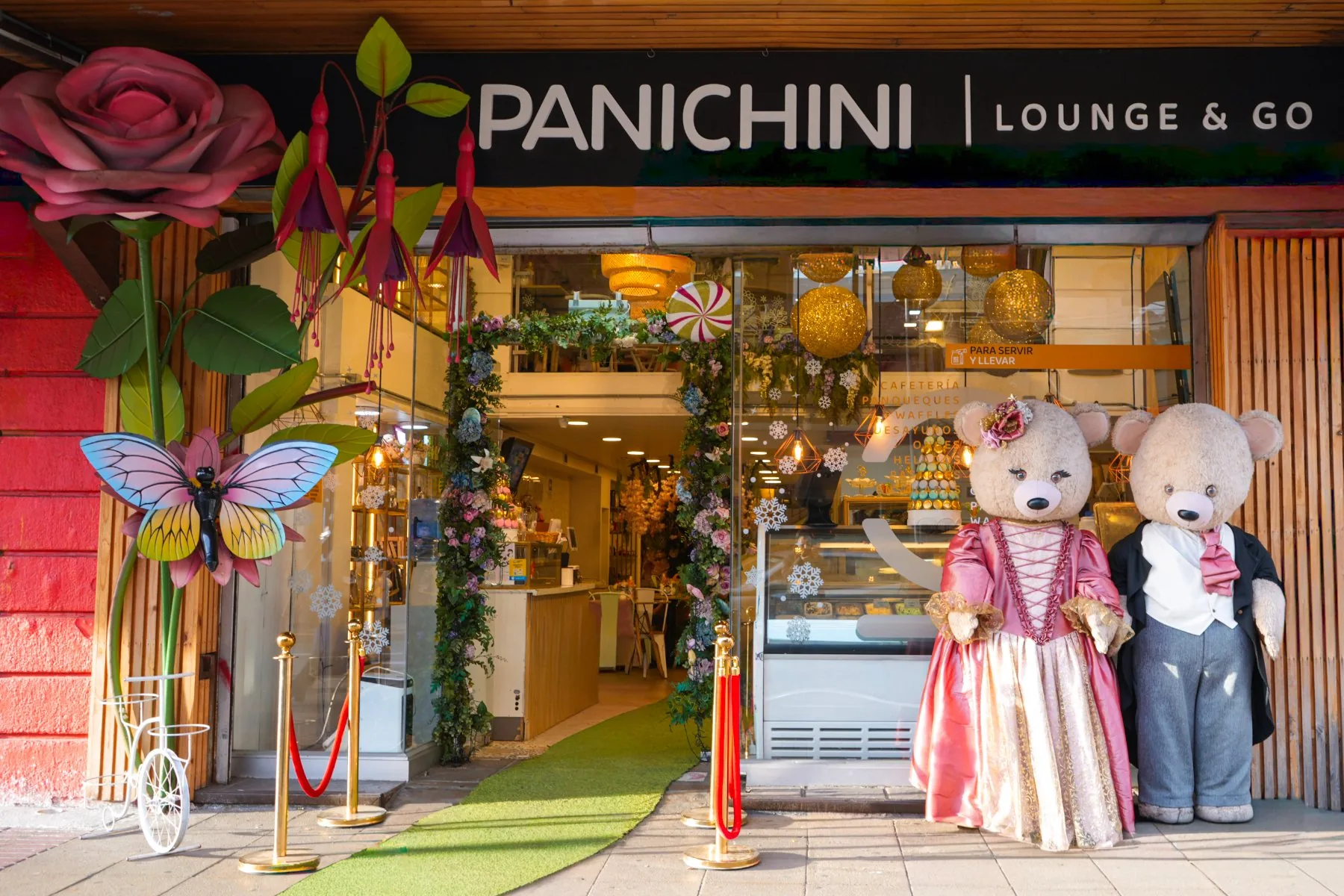 Fachada de Panichini Lounge & Go: rosa gigante, mariposa, alfombra verde y dos ositos de gala