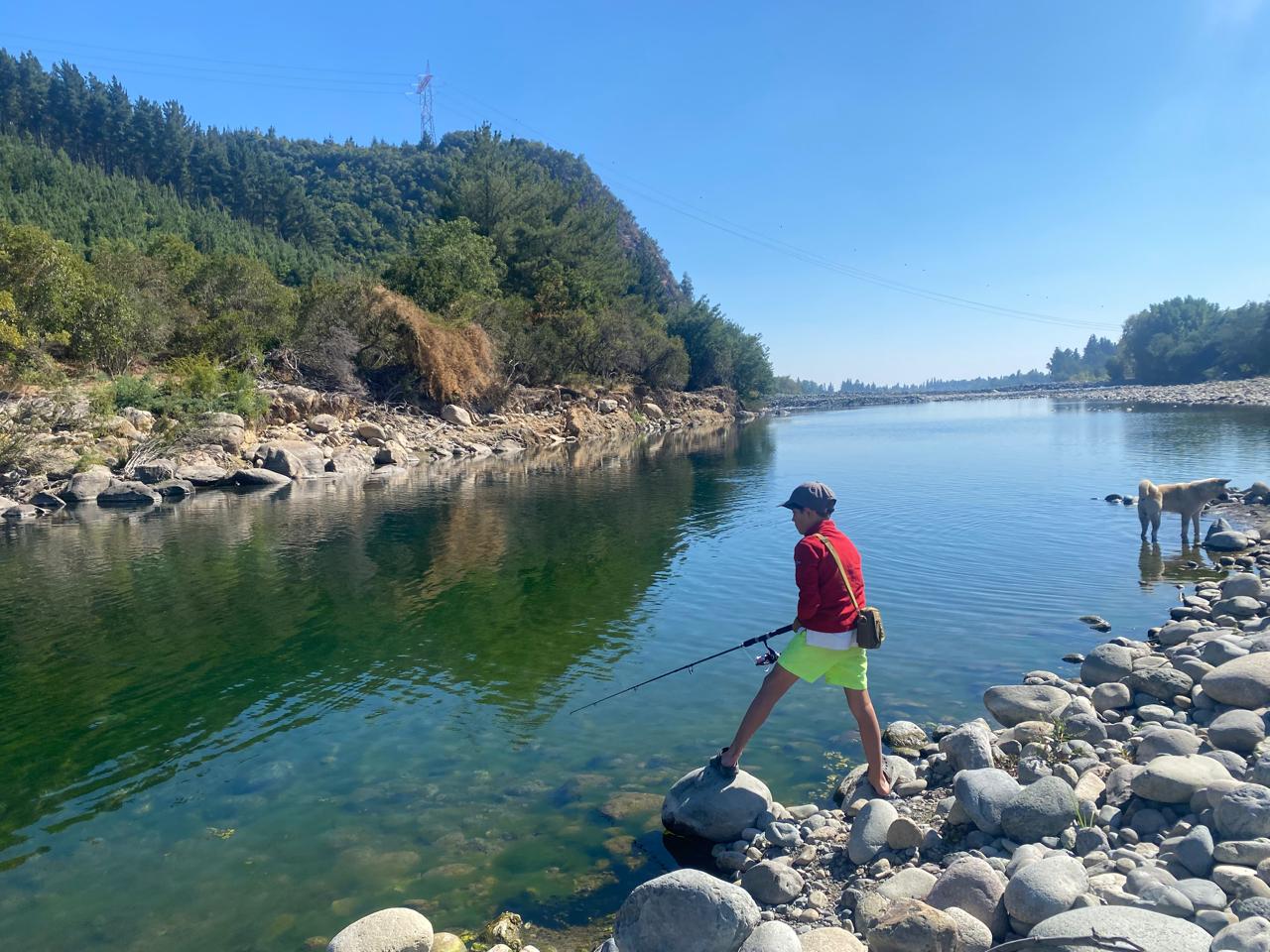 Niño pescando en río chileno con caña de spinning — El Refugio tienda de pesca Chile