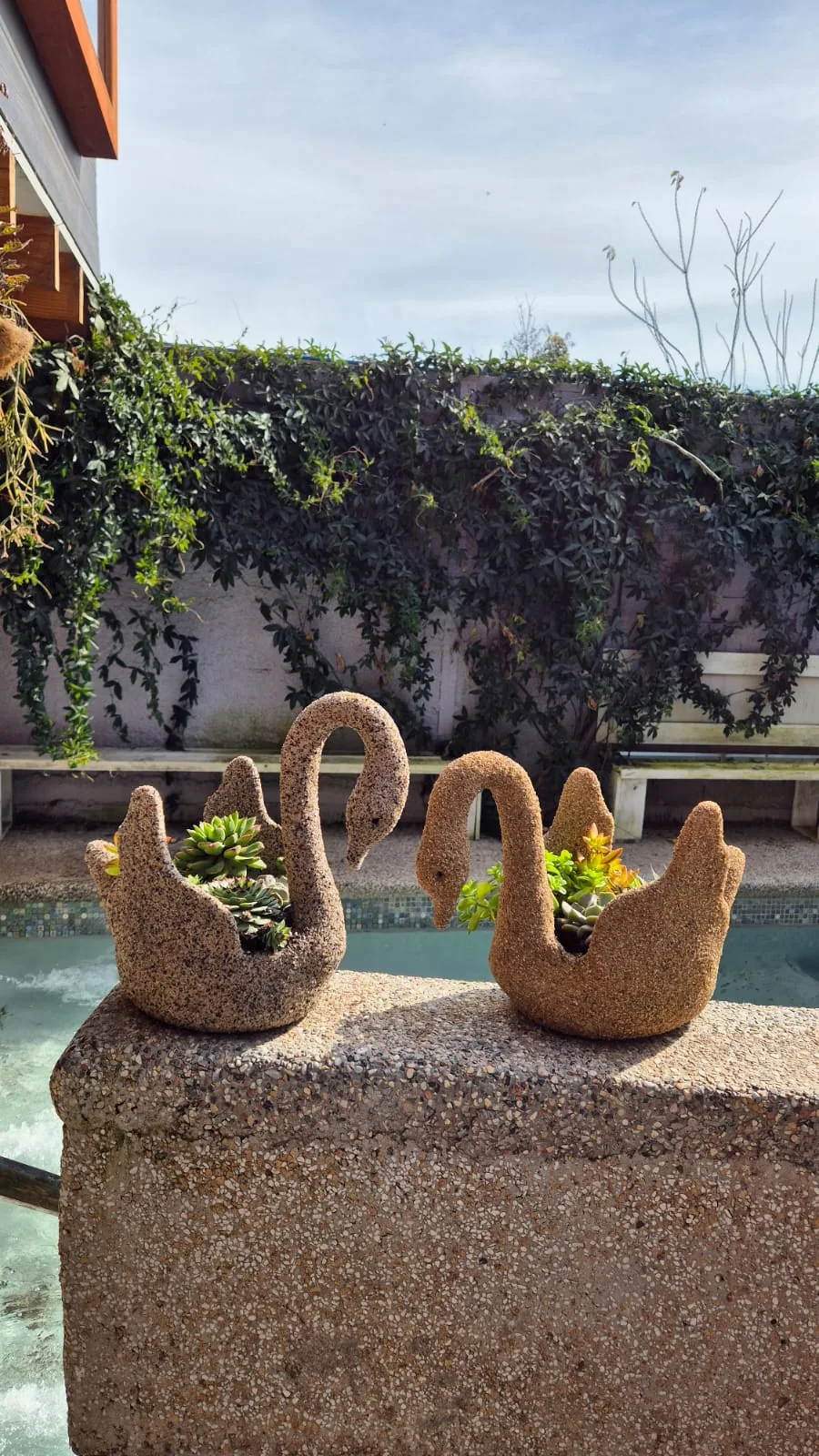 Maceteros artesanales con forma de cisne junto a un jardín