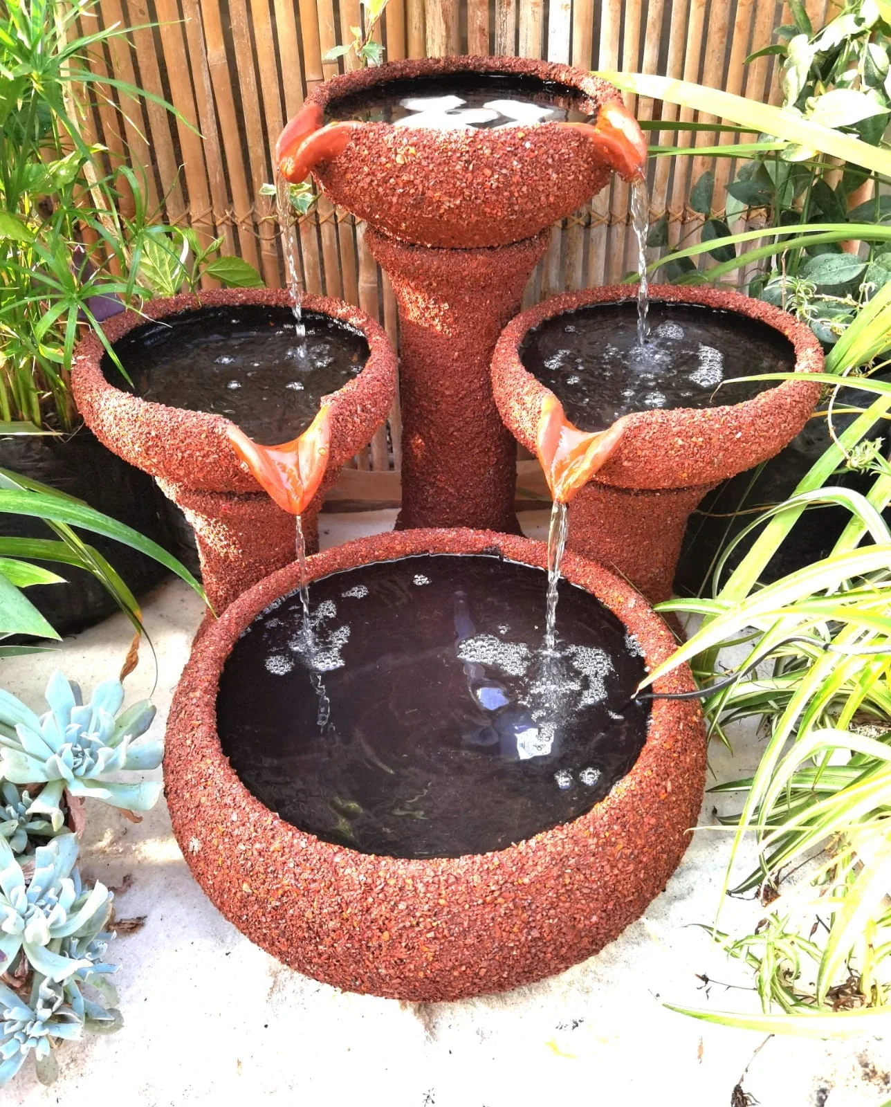 Agua cayendo entre los tres cuencos de una fuente artesanal