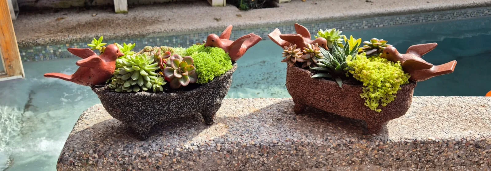 Dos maceteros decorados con pájaros y plantas en un espacio exterior