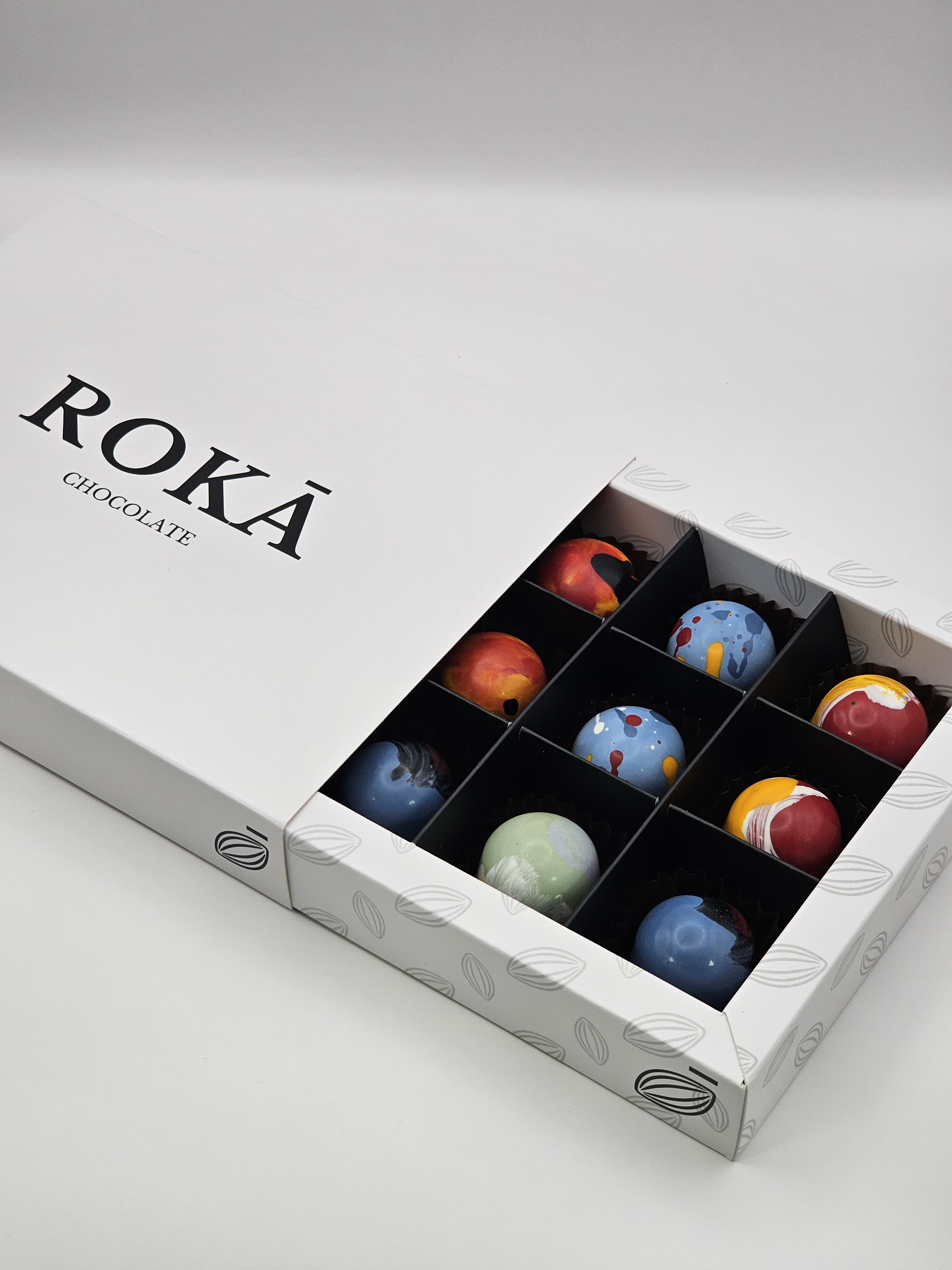ROKĀ CHOCOLATE<br><span style="font-family: 'Playfair Display', Georgia, serif; font-size: 0.6em; color:#FFFFFF;">La ciencia del templado y el arte de la pincelada en cada pieza.</span><br>