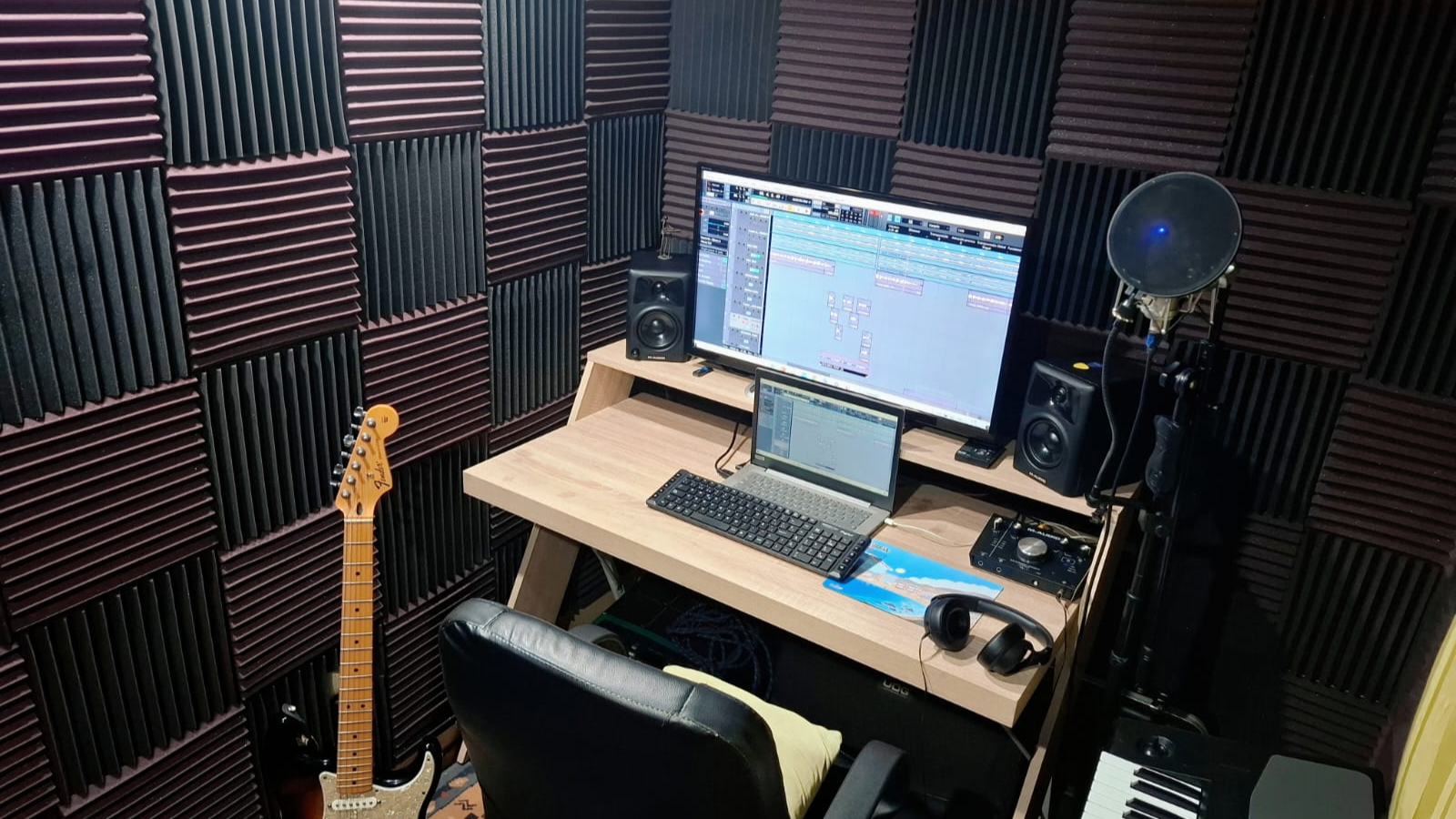 Micrófono de estudio frente a paneles acústicos verdes y negros para aislamiento sonoro profesional.