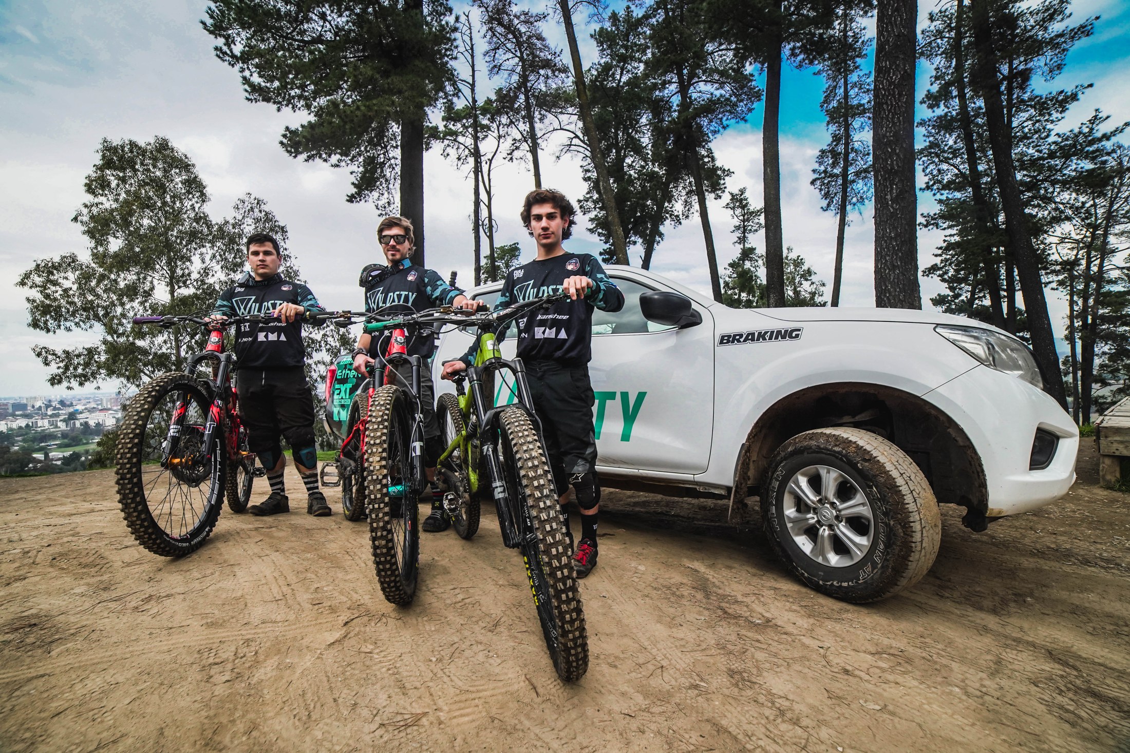 Tres riders con sus bicicletas junto a una camioneta WILDSTY